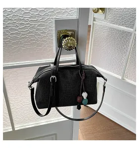 Detailed view of a black textured canvas tote bag hanging on a vintage white door handle