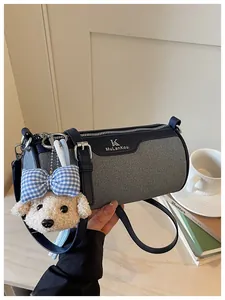Close-up of a stylish gray cylindrical crossbody bag with a cute puppy plush charm