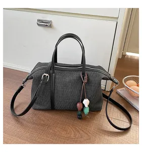 Detailed view of a gray canvas shoulder bag with a unique beaded charm ornament.