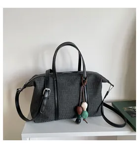 Detailed view of casual gray canvas tote bag with black trim and decorative bead charm
