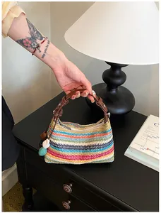 Gros plan d'un sac à main en paille tressée aux couleurs de l'arc-en-ciel avec anse brune.
