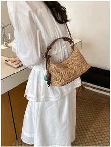 Vue détaillée d'un sac bandoulière en paille avec perles colorées sur un modèle en robe.