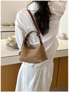Sac à bandoulière en paille tressée avec lanière en cuir porté par un modèle.