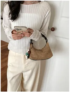 Détail d'un sac d'épaule en paille bohème avec un charmant pendentif coloré en perles