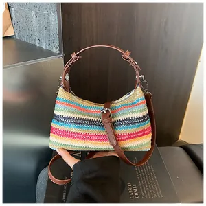 Détail d'un sac à bandoulière tissé à rayures arc-en-ciel avec lanière en cuir brun.