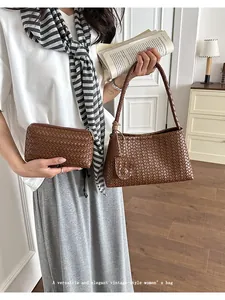 Elegant brown woven underarm bag and matching clutch pouch shown in a stylish lifestyle setting