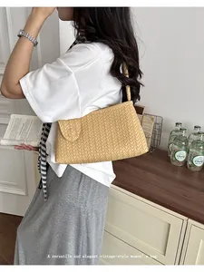 Elegant beige woven underarm bag held by model in a casual lifestyle indoor setting