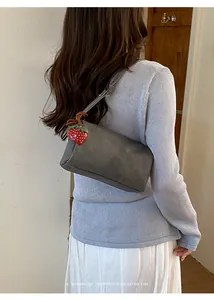 Detailed view of grey minimalist pillow bag featuring a cute red strawberry charm