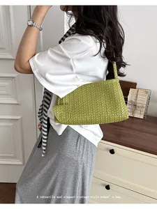 Side view of a vibrant green woven underarm bag styled with a casual summer outfit.