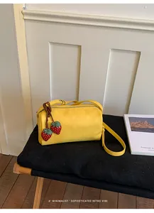 Detail shot of a chic yellow barrel shoulder bag with cute strawberry charms on a bench