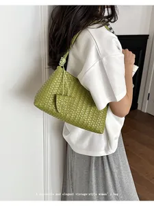 Elegant green woven intrecciato style shoulder bag shown on a model in a minimalist setting
