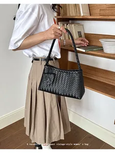 Detailed view of an elegant black woven underarm bag with vintage minimalist design