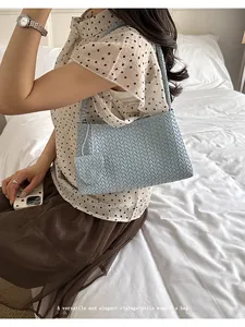 Close-up of elegant light blue woven shoulder bag styled by an Asian model in bed