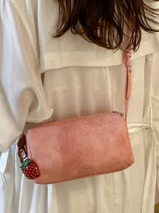 Minimalist pink crossbody pillow bag for women featuring a cute strawberry charm pendant.