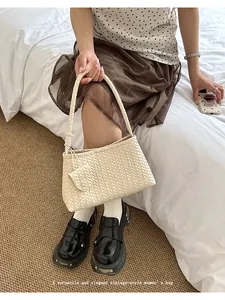 Close-up detail of elegant cream woven hobo bag featuring a matching mini coin pouch accessory