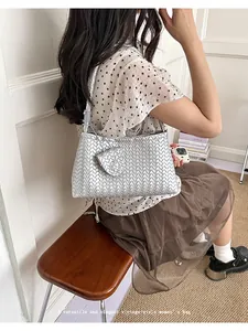 Close-up of a stylish silver woven underarm bag carried by a model in a vintage summer outfit