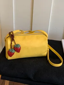 Vibrant yellow crossbody pillow bag for women with cute strawberry charm