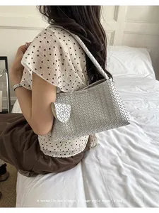 Detail of elegant silver woven underarm bag shown in a lifestyle indoor setting