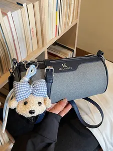 Elegant blue cylindrical crossbody bag featuring a cute teddy bear plush charm accessory