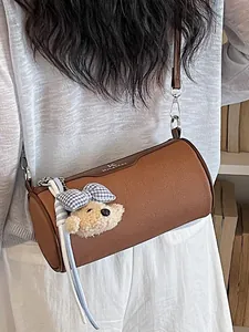 Stylish brown cylinder crossbody bag for women featuring a cute plush bear charm.