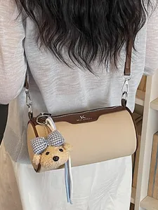 Elegant minimalist beige cylindrical crossbody barrel bag featuring a cute plush bear charm