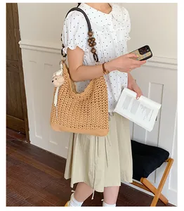 Detail shot of a woman holding a beige woven straw tote bag with wooden beaded straps