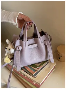 Détail du sac à main lavande en cuir texturé avec des nœuds décoratifs et un lapin
