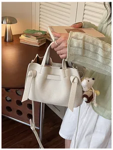 Vue détaillée d'un élégant sac cabas en cuir crème avec breloque ours