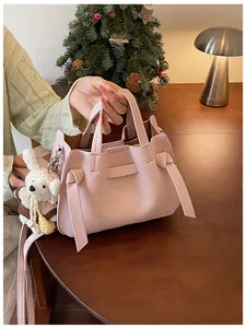 Détail du sac cabas en cuir rose avec un charm lapin mignon et design à nœuds