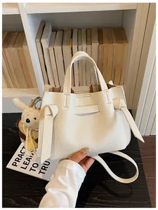 Gros plan d'un sac à main en cuir grainé blanc cassé avec des nœuds latéraux élégants.