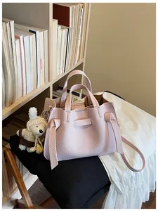 Détail d'un sac cabas en cuir rose avec des lanières latérales nouées dans un décor intérieur