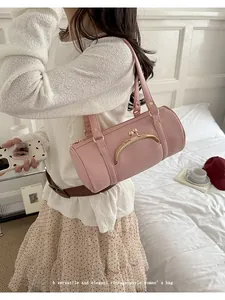 Detail of a pink vintage kiss-lock barrel bag carried by a woman in a casual setting