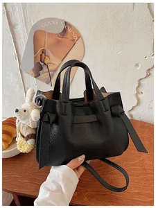 Gros plan sur un sac cabas élégant en cuir grainé noir avec des nœuds et un pendentif