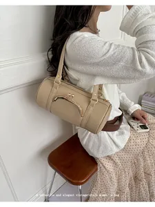 Elegant khaki vintage-style barrel bag worn by a model in a minimal setting.