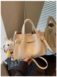 Vue détaillée d'un sac cabas en cuir crème avec un joli porte-clés lapin pour femme.