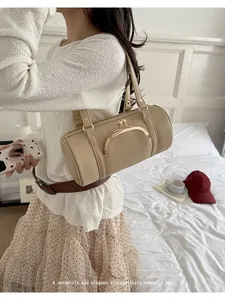 Detailed view of the vintage-style beige cylindrical underarm bag with kiss-lock clasp.