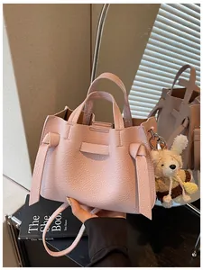 Détail du sac cabas en cuir rose grainé avec breloque lapin et détails de nœuds