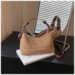 Élégant sac à bandoulière en paille tressée avec lanière en cuir marron sur un livre