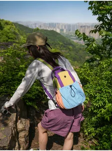 Detail view of a vibrant multi-colored outdoor backpack worn by an active hiker.