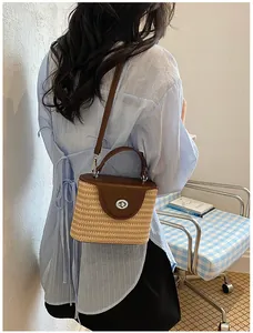 Vue lifestyle d'un sac seau en paille tressé à la main porté élégamment à l'épaule.