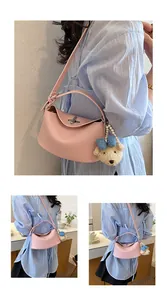 Dettaglio di una borsa rosa martellata con ciondolo a orsetto indossata dalla modella.