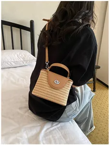 Élégant sac seau en paille tressée à la main avec rabat en cuir brun et fermoir rotatif