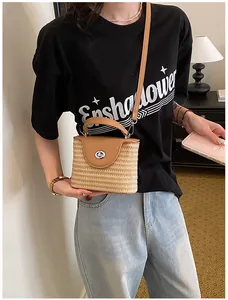 Détail d'un sac seau en paille tissé avec rabat et bandoulière en cuir
