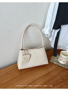 Detailed view of an elegant beige woven shoulder bag placed on a vintage wooden desk