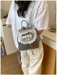 Silver mini backpack with lace trim and cartoon dog, shown being worn by a person.