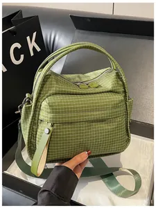 Detail of a casual green grid nylon crossbody handbag with zipper pocket and handle
