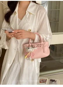 Dettaglio di una borsa rosa strutturata con un grazioso ciondolo a forma di orsetto.