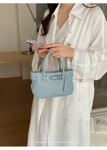 Elegante modella asiatica con una mini borsa tote azzurra minimalista con fibbia chic