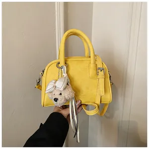 Detail of vibrant yellow pillow bag featuring a cute teddy bear plush charm and handle