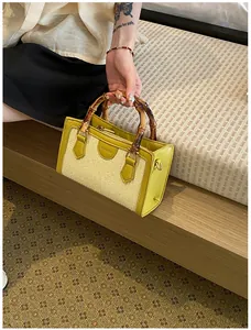 Close-up detail of a vibrant yellow woven straw handbag featuring natural bamboo top handles